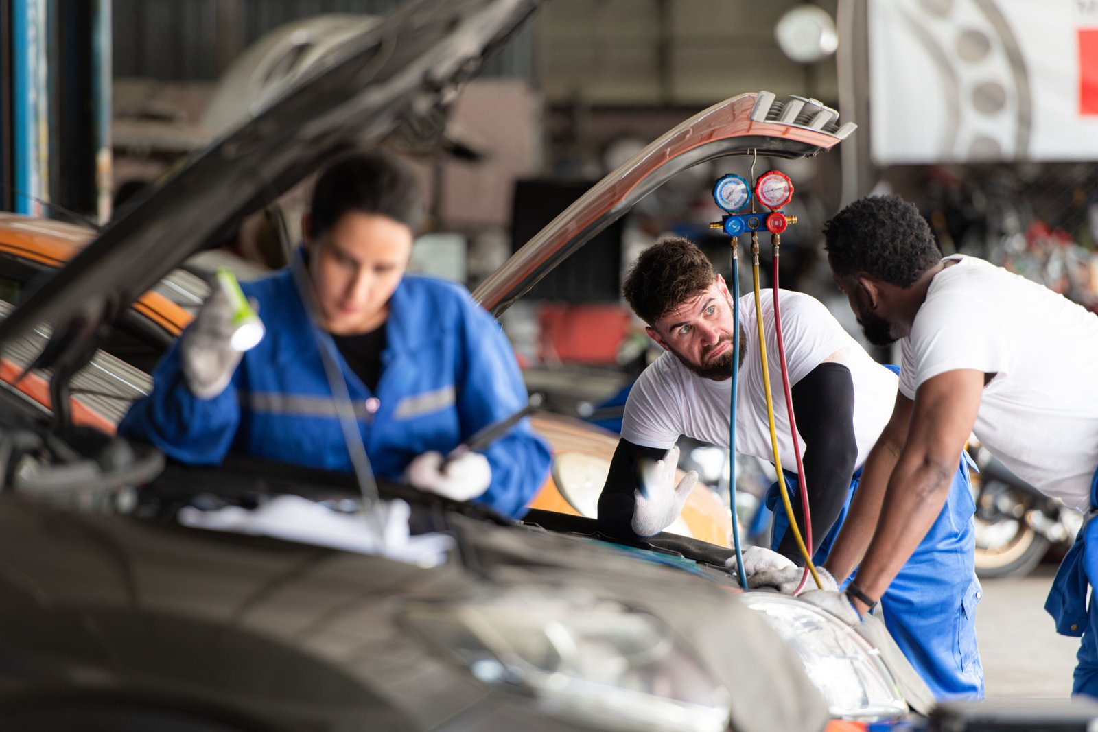 Car mechanic working in an auto repair shop, inspecting the operation of the car's air conditioner and refrigerant, Focus on woman